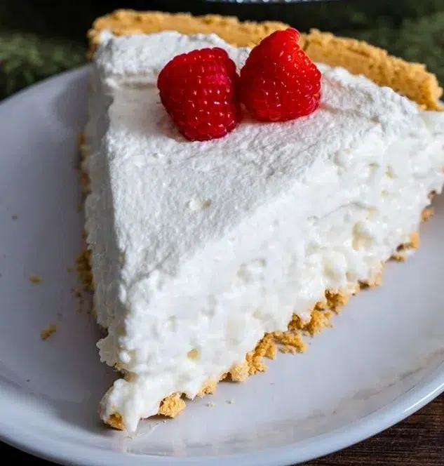 A slice of delicious White Christmas Pie decorated with whipped cream and cherries