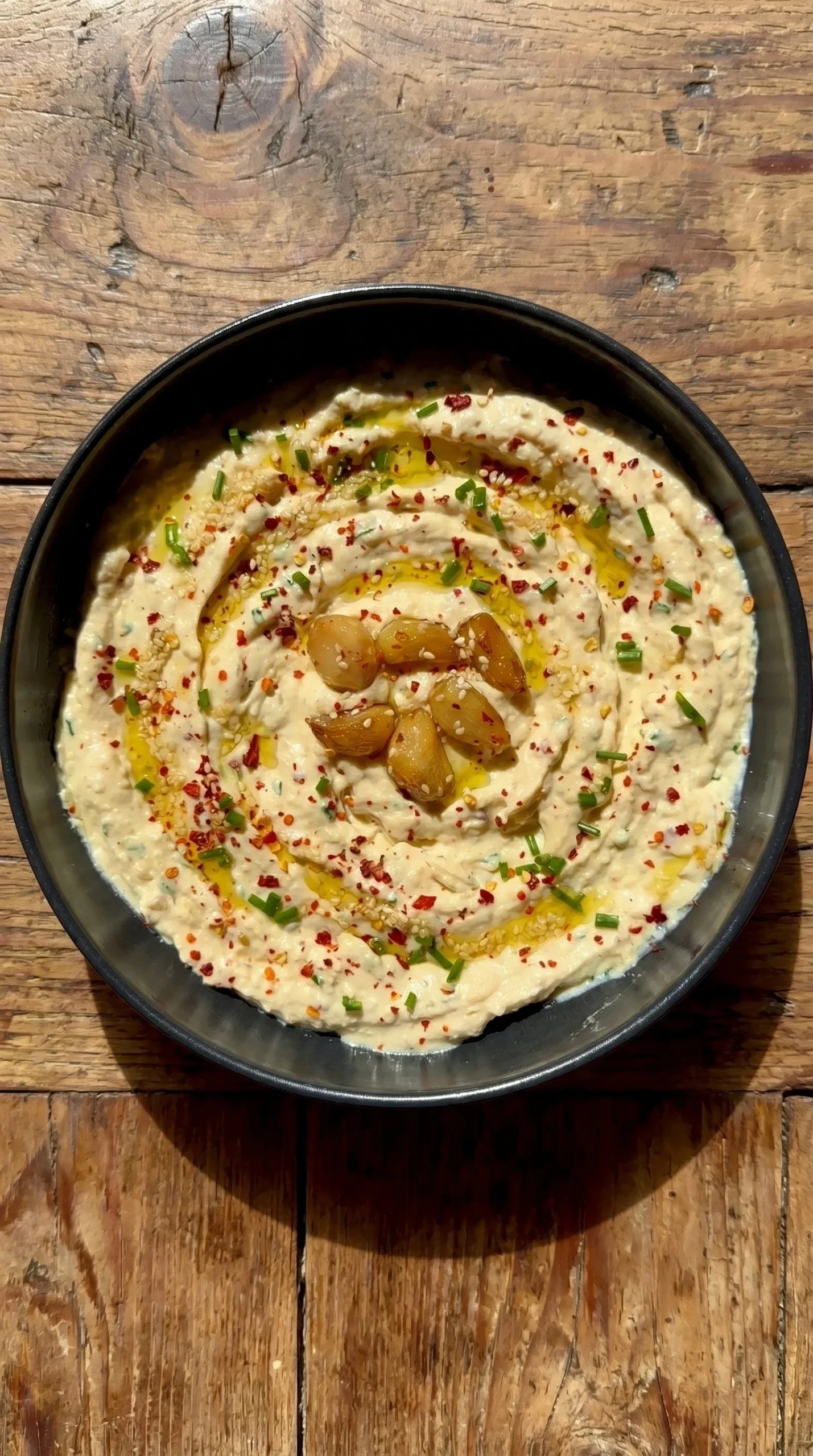 Creamy roasted garlic dip served in a bowl with fresh herbs and breadsticks