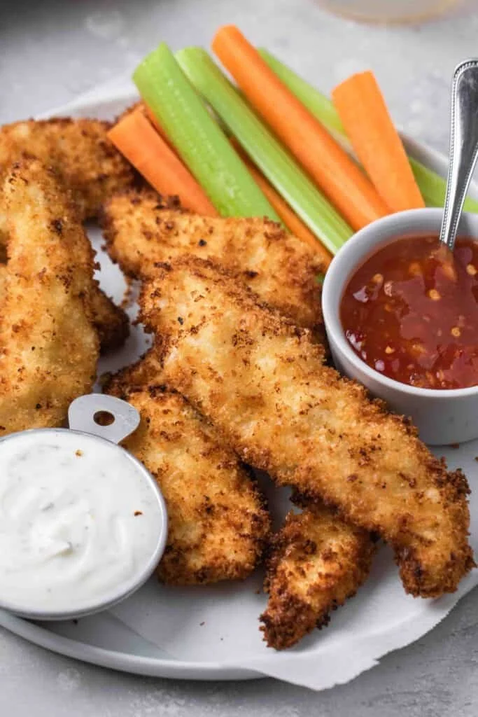 Plate of crispy air fryer chicken tenders garnished with herbs