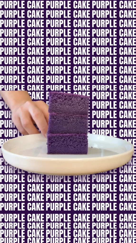 Slice of Ube Coconut Cake with purple and white frosting on a wooden table.